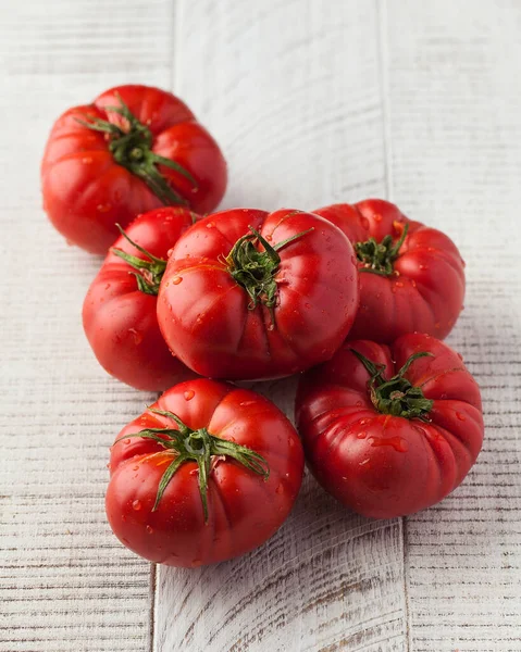 stock image Ripe fragrant tomatoes on a white wooden background. The concept of seasonal vegetables.