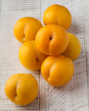 Beyaz ahşap bir masada olgun sarı erik. Hasat konsepti, meyveler..