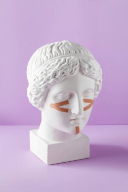 Mor arka plandaki büstteki yüz için bej kasetler. Cerrahi olmayan yüz gerdirme, gençleştirme kavramı..