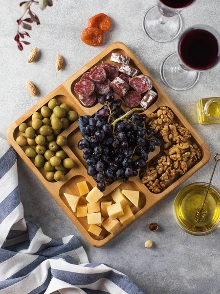 Snacks for wine in a wooden menagerie. Cheese, sausages, berries in a wooden plate, festive serving of snacks.