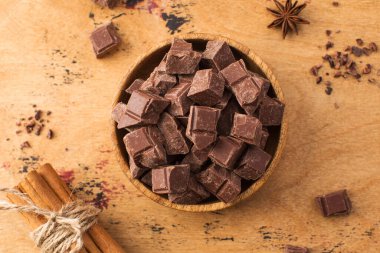 Tahta bir arka planda tahta bir kasede organik süt çikolatası küpleri. Çikolata konsepti.