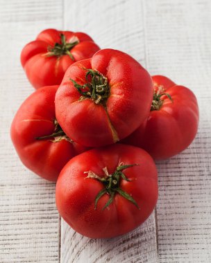 Beyaz ahşap arka planda olgun kokulu domatesler. Mevsimlik sebze kavramı.