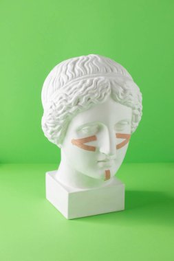 Yeşil arka plandaki büstteki yüz için bej kasetler. Cerrahi olmayan yüz gerdirme, gençleştirme kavramı..