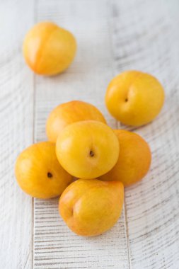 Beyaz ahşap bir masada olgun sarı erik. Hasat konsepti, meyveler..