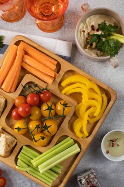 Tahta bir tabakta taze sebzelerin karışımı. Vejetaryen atıştırması. Biber parçaları, menazhnitsa üzerine humuslu kereviz. Vejetaryenlik.