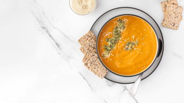 Patates püresi ve çekirdekli bir kase balkabağı çorbası bir ışık masasında duruyor. Sonbahar menüsü konsepti. Kolay vejetaryen tarifleri. Boşluğu kopyala