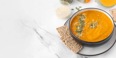 Patates püresi ve çekirdekli bir kase balkabağı çorbası bir ışık masasında duruyor. Sonbahar menüsü konsepti. Kolay vejetaryen tarifleri. Boşluğu kopyala