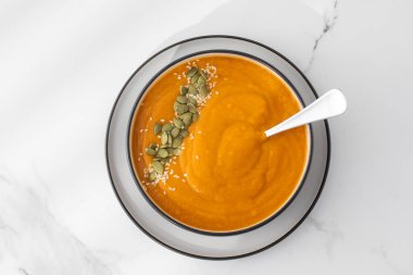 Patates püresi ve çekirdekli bir kase balkabağı çorbası bir ışık masasında duruyor. Sonbahar menüsü konsepti. Kolay vejetaryen tarifleri.