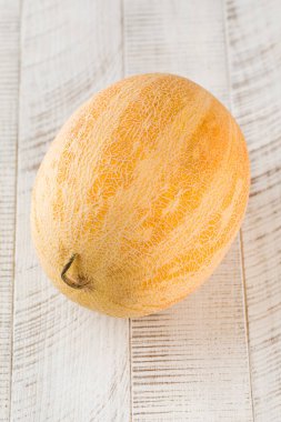 Hafif ahşap zemin üzerinde olgun sulu oval kavun. Meyve konsepti.