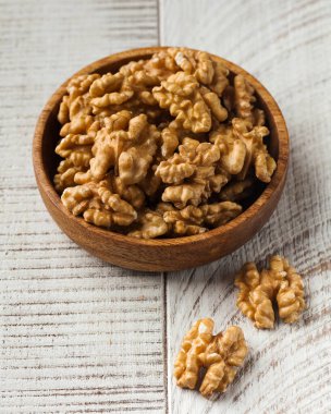 Ahşap arka planda ahşap bir kasede soyulmuş ceviz. Sağlıklı yeme kavramı, fındık.