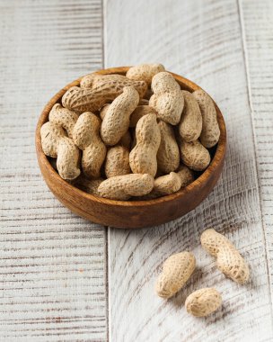 Beyaz ahşap arka planda tahta bir kasede kabuktaki fıstıklar. Sağlıklı yeme kavramı, fındık.