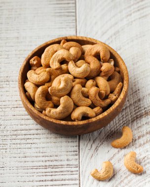 Ahşap arka planda ahşap bir kasede kavrulmuş kaju fıstığı. Sağlıklı yeme kavramı, fındık.