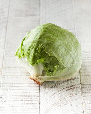 Beyaz ahşap arka planda sulu buzdağı marulu. Sağlıklı beslenme kavramı.