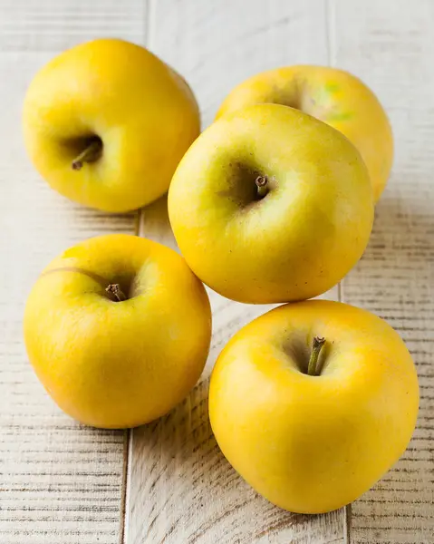 Yellow juicy ripe apples on a white wooden background. The concept of fruit harvesting