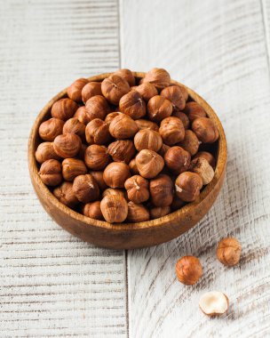 Ahşap bir arka planda ahşap bir tabakta kurumuş fındık kabuğu. Sağlıklı yeme kavramı, fındık.