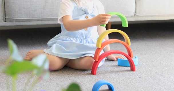 かわいい女の子は 部屋の床に座って木製の虹で教育ゲームをしている 子供の木製の教育玩具 子供の発達と学習 — ストック動画