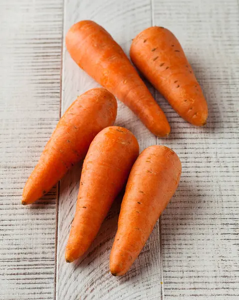 A pile of carrots on a white wooden background. The concept of vegetables, harvesting.