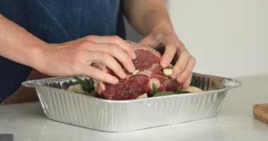 Şef pişirmeden önce çiğ sebzelere bir parça kuzu eti koyar. Tabağı pişirme süreci. Video 4K formatında. Video tarifi