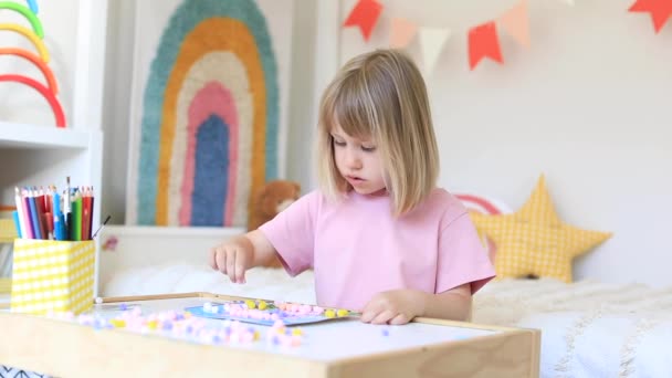 一个可爱的小女孩正坐在桌旁 与五彩缤纷的花环玩耍 做着一只可爱的工艺品 儿童发展 教育概念A — 图库视频影像