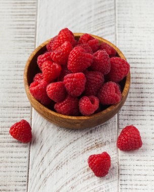 Beyaz ahşap arka planda ahşap bir kasede olgun sulu ahududular. Böğürtlen konsepti, hasat.