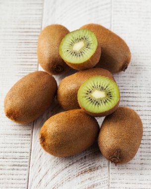 Beyaz ahşap arka planda olgun sulu yeşil kiviler. Meyve toplama konsepti.