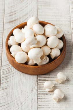 Hafif arka planda, ahşap tabakta taze mantarlar. Mantar konsepti