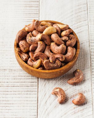Ahşap bir arka planda ahşap bir tabakta kavrulmuş kaju fıstığı. Fındık kavramı.
