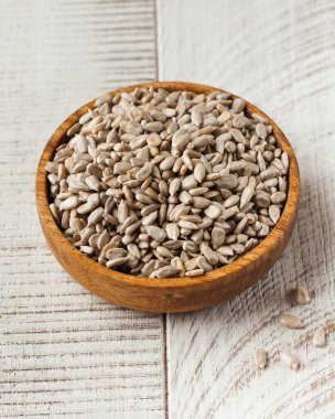 Ahşap bir arka planda, ahşap bir kasede soyulmuş ayçiçeği tohumları. Tohum kavramı.