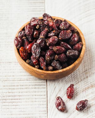 Beyaz ahşap bir arka planda tahta bir tabakta kurumuş gül ağacı.. 