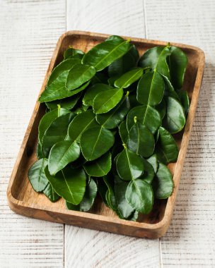Taze bergamot yaprakları ya da beyaz ahşap arka planda kaffir kireç yaprakları. Baharat, baharat konsepti. 