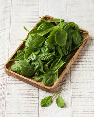 Beyaz ahşap arka planda taze, sulu ıspanak. Yeşillik kavramı