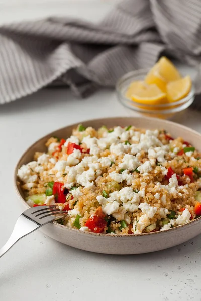Quinoa salad with cheese and fresh vegetables on a plate. The concept of vegetarian recipes.