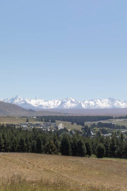 Karlı dağlardan oluşan güzel bir manzara ve Yeni Zelanda vadisinde bir köy. Seyahat kavramı.