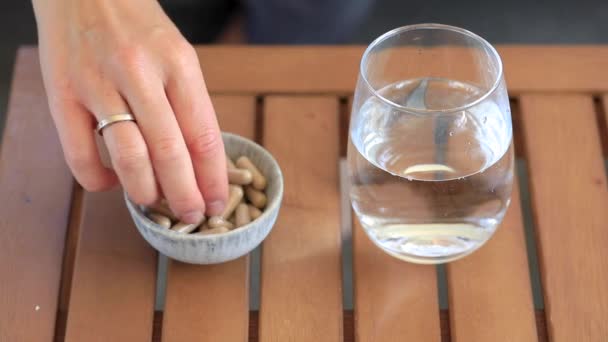 Woman Takes Brown Pill Bowl Table Concept Taking Dietary Supplements — Stock Video