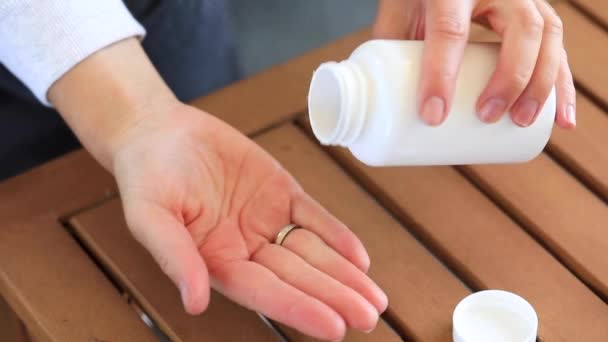 一个女人把白色的药丸或维生素从罐子里倒入她的手掌 健康和营养补充剂的概念 — 图库视频影像