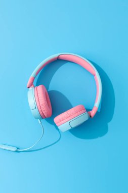 Mavi arka planda parlak kulaklıklar. Müzik ve teknoloji kavramı.