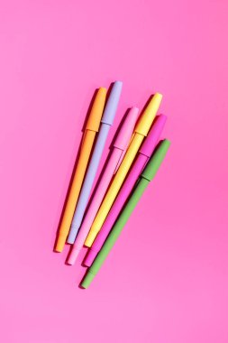 Pembe arka planda parlak renkli renkli kalemler. Ofis malzemeleri konsepti. Okula dönelim. Düz yatıyordu