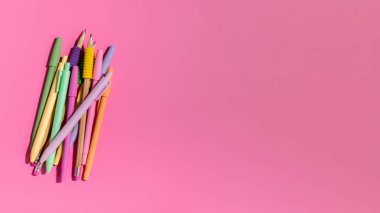 Pembe arka planda parlak renkli renkli kalemler. Ofis malzemeleri konsepti. Okula dönelim. Düz yatıyordu. Boşluğu kopyala