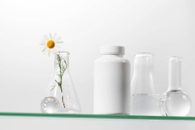 Vitaminli beyaz bir kavanoz ya da cam rafta bitkisel ilaçlar. İlaç konsepti, biyolojik olarak aktif maddeler..