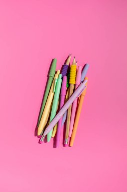 Pembe arka planda parlak renkli renkli kalemler. Ofis malzemeleri konsepti. Okula dönelim. Düz yatıyordu