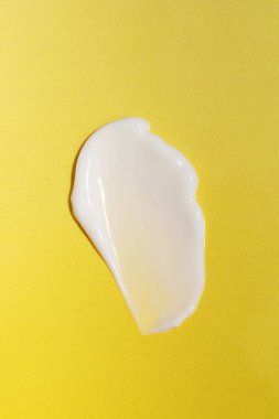 Örnekler. Beyaz bir kozmetik ürünün dokusu, sarı arka planda krem. Cilt bakımı kozmetik ürünleri. Cilt bakımı