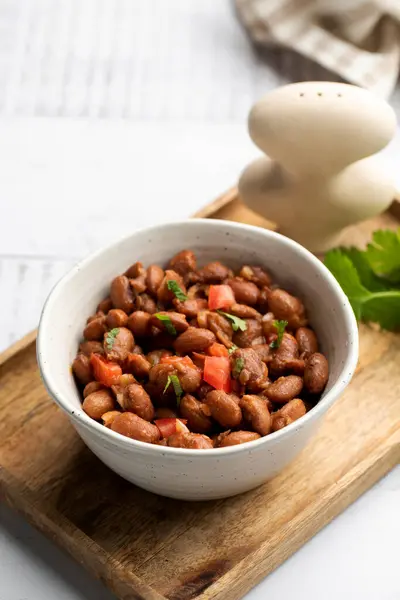 Vegetarian dish of stewed pink beans and tomatoes. A delicious bean dish served on a wooden table.