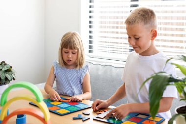 Erkek ve kız kardeş oturma odasında eğitici ahşap mantık oyunları oynuyorlar. Montessori sistemine göre çocuk gelişimi kavramı