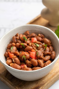 Tahta bir masada sunulan fasulye, domates ve kişnişten yapılmış lezzetli bir yemek. Bu tarif baklagillerden gelen malzemeleri taze ürünlerle birleştirir.