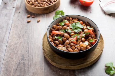  Vejetaryen yemeği, haşlanmış pembe fasulye ve domates. Tahta masada servis edilen lezzetli bir fasulye yemeği..