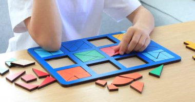 Bir çocuk odadaki masada mantıklı bir ahşap oyun oynuyor. Çocuklar için ahşap eğitim oyuncağı. Çocuk gelişimi ve eğitim.