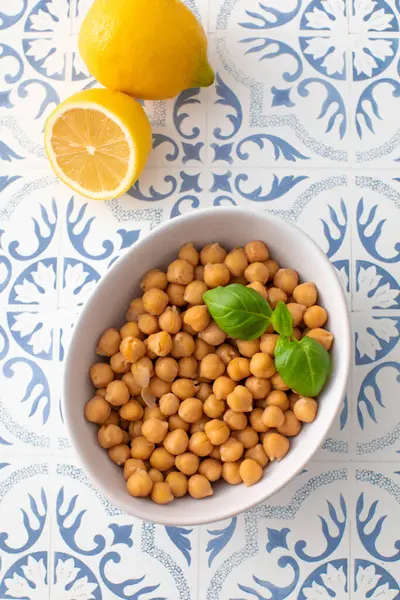 Canned chickpeas in a bowl with a basil leaf on the table. The concept of vegetable protein.