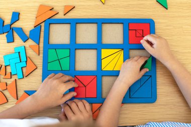 Çocuklar masada ahşap bir yapbozla oynuyorlar. Montessori yöntemini kullanan çocuklar için eğitici mantık oyuncakları.