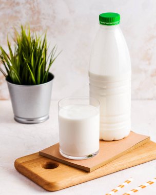 Plastik şişede taze süt, tahta tahtada bardak, sağlıklı içecek konsepti. Süt 
