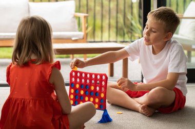 Kardeşler stratejik bir oyuna daldılar, mantığını ve bağlarını geliştirdiler. Çocuklar masa oyunu oynarlar. Dördü bir arada. Mantık oyunu